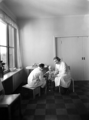 Fredrik Eens Minne, hem för ensamma mödrar.
Daghem, interiör.
Två kvinnor med vita rockar samt barn.