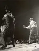 Popartisten Tommy Steele med gitarr på scen, tillsammmans med basist.