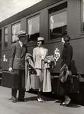 Reseeffekter, Nordiska Kompaniet.  Två kvinnor och en man med varsin resväska utanför järnvägsvagn.