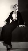 Dammode. Visning av Nordiska Kompaniets höstkläder den 16 september 1933. Kvinnlig modell i mörk kort jacka med vida ärmar nertill, ljust linne under. Lång mörk kjol