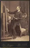 Konstnären Julius Kronberg (1850-1921) målar vid sitt staffli. Kabinettsporträtt.