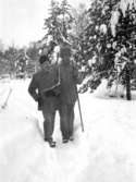 Två män promenerar i skogen på vintern.