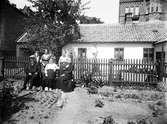 Brevbärare Rosén familj. En grupp människor framför ett hus med trädgård. Kvarteret Österbro, Östergatan 4. Brevbärare Rosén.