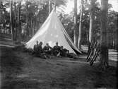 Militärer framför tält i skogen