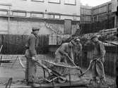 Byggnadsarbetare arbetar med cementgjutning på bygge i Uppsala 1950