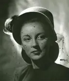 Porträtt av kvinna i hatt med fjäder och flor med moucher.