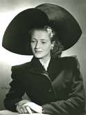 Porträtt av kvinna med bredbrättad hatt i svart filt och sammet. Hatt använd vid franska avdelningens uppvisning september 1947.