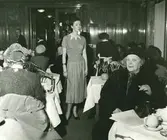 Modevisning på Nordiska Kompaniet. Modell klädd i kortärmad tröja, plisserad kjol och pumps.