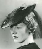 Fb, Porträtt av kvinna med hatt. Svart baku, svart flor, nål i glas och metall.
