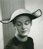 Porträtt av kvinna i hatt med flor, av Gilbert Orcel.