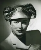 Porträtt av kvinna i turkosfärgad filthatt med mjuka fjäderfantasier. Modell från Gilbert Orcel.