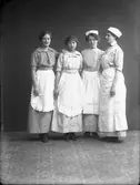 Gruppfoto av kvinnor iklädda förkläden och huvudbonad