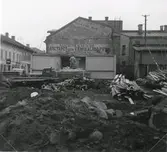 Rivningen av Fastens Café, kv Prosten 8 vid första hälften av 1950-talet. På gaveln ses reklamtext för Maritz Lundhs Färg, tapet och kemialieaffär i handlande Lindströms hus, samt rum för resande.