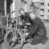 Två unga män undersöker en motorcykel utanför Nils Svenssons Cykel och Motor