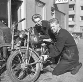 Två unga män undersöker en motorcykel utanför Nils Svenssons Cykel och Motor