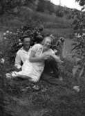 Ett par sitter tillsammans på marken i en trädgård