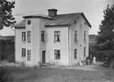 Enköping, Familjen Herkes hus, sett från nordost. De två äldre på bilden är sannolikt paret Herke. Paret flyttade dit 1897. Huset revs i och med att nuvarande tre hyreshus byggdes 1941.