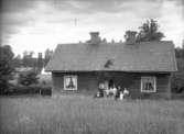 Familj framför hus, oidentiferat