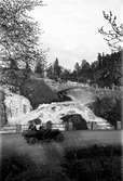 År 1924-06-01. Ådalsvägen i Huskvarna. En bil är på väg uppför och det är mycket vatten i fallen.