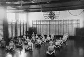 Pojkar i gymnastiksal på Krokslättsskolan. De sitter på led med korslagda ben.