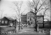 Barn och lärare leker ringlekar utanför Kärraskolan (Kärra skola), 1910-tal. Skolan låg mellan Kärragatan och Kråketorpsgatan, nuvarande Åbro industriområde och Kärra i Mölndal.