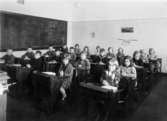 Elever sittande i sina bänkar med knäppta händer på Kvarnbyskolan i Mölndal ca 1930.