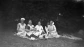 Fyra kvinnor och en man sitter på en filt utomhus: Valborg, Maria och sommargäster. Hallen i Kållered, 1930-tal.