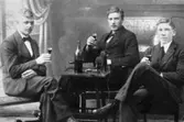 Tre män i kostym sitter runt ett bord med var sitt glas i handen. Från vänster: man med okänd identitet, Ivar Dahlberg och Willy Jansson. Mölndal, okänt årtal.
