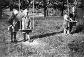 Bosgårdens barnträdgård 1938. Fyra barn som står parvis vid var sin gunga.