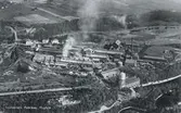 Flygfoto med Ljungaverksfabriken mitt i odlingslandskapet. I förgrunden syns en del av Ljungan. Vykort.