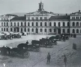 Bilden visar Stadshuset före stadsbranden 1888. Framför Stadshuset Stora torget med torghandel och ett antal droskor med kuskar.
Bildtext på vykortet 