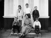 Fem pojkar poserar tillsammans med Valdeborg Johansson som sitter i mitten, våren 1934. Hon är med sina elever utanför skolan. Text på fotots baksida: 
