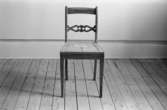 En stol i Karl Johanstil med genombruten tvärslå. 
Stolen är fabrikstillverkad i Småland efter en Lindomemodell.