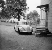 En folkvagn utanför entrén till en av Papyrus arbetarbostäder på Brunnsgatan 1-9. I bakgrunden syns Klevgatan 2. 1960-tal.