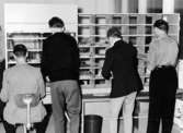 Postkontoret Danderyd 1.
Fr.v. brevbärarförman K.E. Mattsson,  postiljon Tommy Svensson, postiljon R. Albinsson och brevbärarförman E. Andersson försorterar.
Foto 19/10 1958.