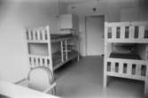 Dokumentation av Sagåsens flyktingförläggning 1992. Ett rum inrett med två våningssängar, skrivbord och stol.