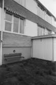Dokumentation av Sagåsens flyktingförläggning 1992. Exteriör vy mot byggnad, gräsmatta, insynsskydd samt bänk.