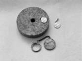 En ca 10 cm rundsvarvad stenplatta med hål i. En nyckelring samt två hängsmycken med inskriptionen 