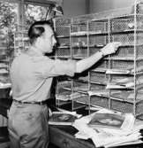 Lantbrevbärare Ingvar Carlsson förbereder brevbäringsturen, på postexpeditionen i Åkersberga.  Augusti 1961.