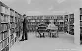 Vykort med interiör från Krokslätts bibliotek, 1960-tal. Ståendes till vänster är Erik Karlén.