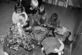 Fem barn sitter på golvet och pysslar med saker som ligger i två näverkorgar. Utställningsvernissage av och om Katrinebergs daghem på Mölndals museum 1993-09-10.