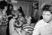 Barn och vuxna som står i entrén till Mölndals museum. Det är fikapaus och barnen dricker ur muggar eller äter kex. Utställningsvernissage av och om Katrinebergs daghem på Mölndals museum 1993-09-10.