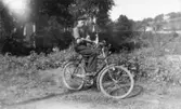 Ivar Karlsson (född 1922, fotografens lillebror) sitter på sin cykel vid Kvarnfallet 31, 1930-tal.