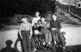 Fyra pojkar, okända för givaren, sitter/står runt en Rex Willers motorcykel i Mölndal. 1950-tal.