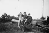 Kusiner som gör honnör sittandes på en kanon utanför Skansen Kronan i Göteborg. Från vänster: Per-Olof Larsson, Leif och Alf Garthman. 1950-tal.