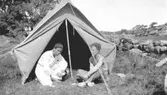 Bror Eriksson och Helmer Garthman spelar kort framför ett upprest tält i Fjärås, 1930-tal.