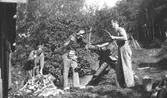 Gustav Andersson, Charlie Jinnerstedt och Helmer Garthman sågar ved vid en sågbock i Fjärås. 1930-tal.