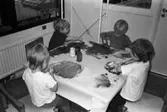Dagisbarnen Henrik, Fred och Alexandra samt okänd sitter och målar teckningar kring ett bord på Lunkentussen, Katrinebergs daghem 1992-93.