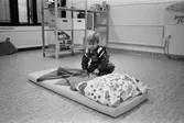 Henrik rättar till filten efter att ha bäddat klart den mjuka madrassen med kudde. Madrassen ligger på golvet i ett lekrum. Lunkentussen, Katrinebergs daghem 1992.