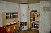 Rum med kakelugn, hyllor och pärmar inne på Gunnebo slott, maj 1995.